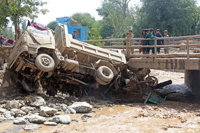 Afghan boys look at a truck that was damaged in flash floods in the Jalrez district of Maidan Wardak province on July 23, 2023. The death toll from overnight flash floods caused by torrential rain in central Afghanistan has risen to 26, with more than 40 people missing, officials said. (Photo by AFP Photo/Stringer)