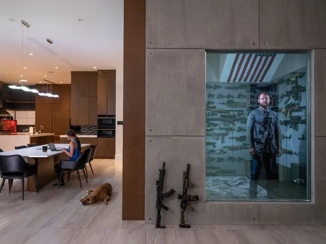 Portraits, first prize – Stories. The “Ameriguns”. Robert Baldwin Jr stands in his secret gunroom, behind a one-way mirror in his home in Las Vegas, Nevada, on 16 April 2019. His girlfriend, Tori, sits at the table. “I like to give myself a gun as a gift to mark important moments, like Christmas or my birthday”. It’s a family tradition. When he turned six, his father gave him his first .22-calibre rifle and taught him how to use it. “He used to shoot for fun. He was a hunter, and he wanted to bring me along, to forge a special bond. He succeeded”. (Photo by Gabriele Galimberti/World Press Photo 2021)