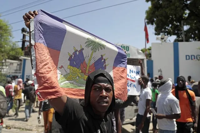 A demonstrator holds up a Haitian flag during a protest against insecurity in Port-au-Prince, Haiti, Monday, August 7, 2023. (Photo by Joseph Odelyn/AP Photo)
