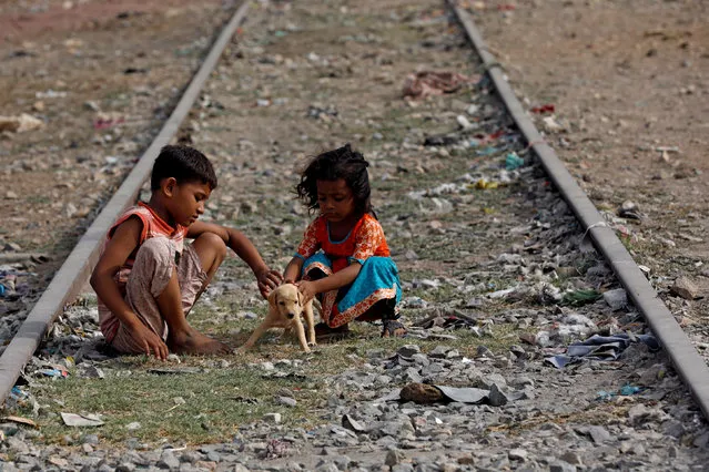 Siblings play with a puppy named Tiger along an old railway track in a low-income neighborhood in Karachi, Pakistan on August 6, 2018. (Photo by Akhtar Soomro/Reuters)