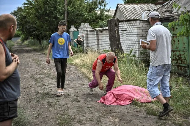A man approches the body of his son who was reportedly killed by a cluster rocket in the city of Lysychansk in the eastern Ukrainian region of Donbas on June 18, 2022 amid the Russian invasion of the country. (Photo by Aris Messinis/AFP Photo)