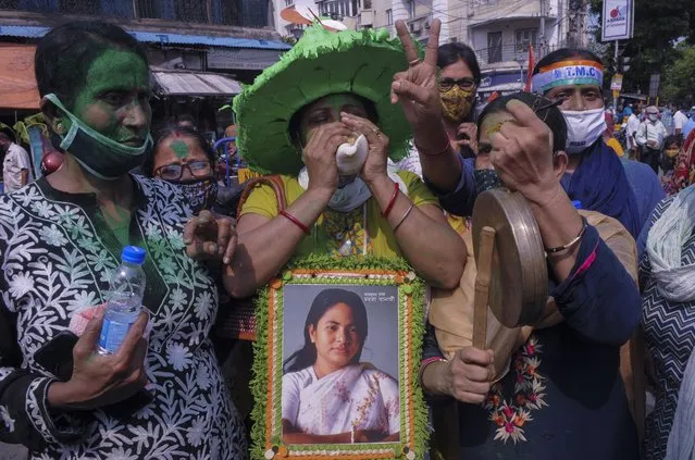 Supporters of Trinamool Congress party chief Mamata Banerjee holding an earlier photograph of her celebrate early lead for the party in the West Bengal state elections in Kolkata, India, Sunday, May 2, 2021. (Photo by Ashim Paul/AP Photo)