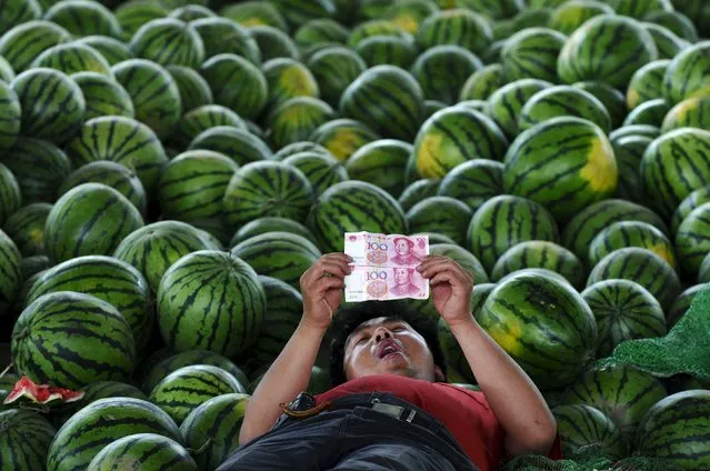 A watermelon vendor looks at yuan banknotes at a market in Changzhi, Shanxi province in this June 21, 2010 file photo. (Photo by Reuters/Stringer)
