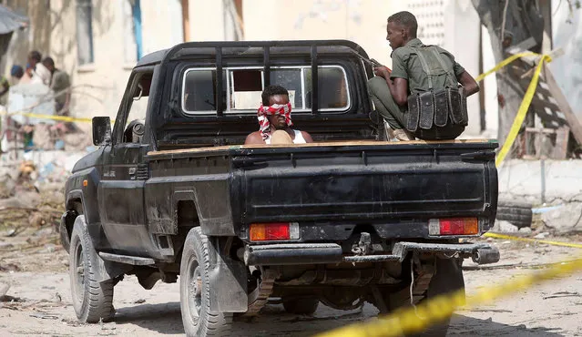 A security officer guards a suspected member of the al Shabaab, who was detained near the Mogadishu port after a suicide car bomb went off at the entrance of the port, in Mogadishu, Somalia December 11, 2016. (Photo by Feisal Omar/Reuters)