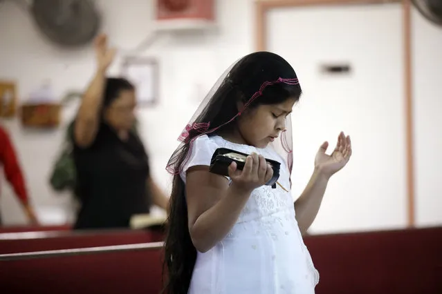 In this Wednesday, September 19, 2018 photo, a girl prays during a church service in Huron, Calif. California may be famous for its wealth, but there is a distinctly different part of the state where poverty prevails: places like this one halfway between Los Angeles and San Francisco. (Photo by Marcio Jose Sanchez/AP Photo)