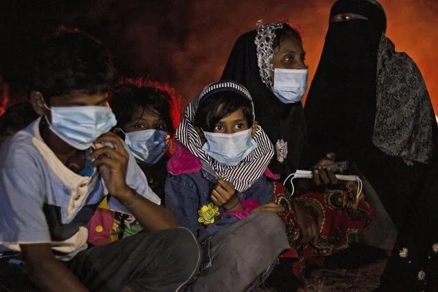 Ethnic Rohingya women and children sit by a fire on a beach after their boat was stranded on Idaman Island in East Aceh, Indonesia, late Friday, June 4, 2021. Villagers in Indonesia's Aceh province discovered a stranded boat Friday carrying dozens of Rohingya Muslims, including children, who had left a refugee camp in Bangladesh, officials said. (Photo by Zik Maulana/AP Photo)