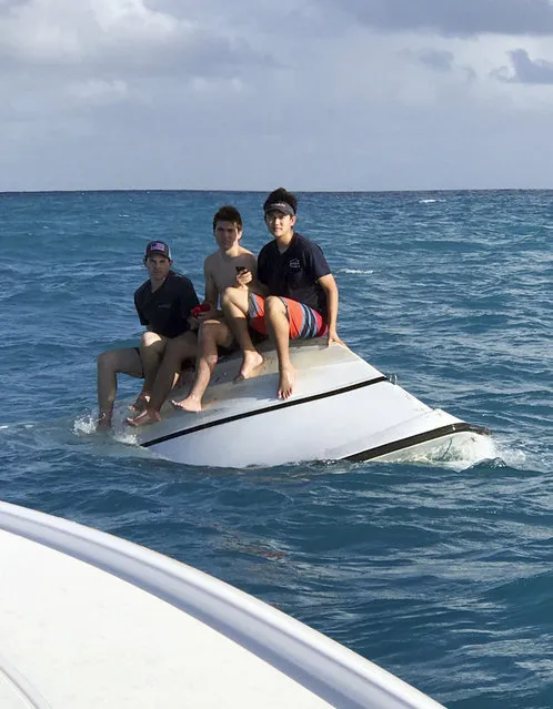 In this Tuesday, December 27, 2016, photo made available by the Florida Fish and Wildlife Conservation Commission, teenagers Zack Sowder, left, Jacob Sowder and Brent Shishido, right, of Orange County, Calif., sit on an capsized vessel offshore of Little Torch Key in the Florida Keys. The stranded teenage boys called 911 and calmly sat atop a capsized boat before being rescued, authorities said Wednesday, Dec. 28.  (Photo by David Bingham/Florida Fish and Wildlife Conservation Commission via AP Photo)