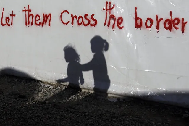 Shadows of children are cast on a tent bearing graffiti at the northern Greek border point of Idomeni, Greece, on May 4, 2016. (Photo by Gregorio Borgia/AP Photo)