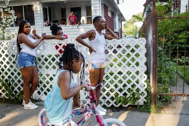 Carolyn Bernard, center, rests her hand on her face while leaning against a fence while across the street police work the scene where a young girl was shot in the leg in an alley on the 11700 block of South Normal Avenue in the West Pullman neighborhood Sunday July 4, 2021, in Chicago. (Photo by Armando L. Sanchez/Chicago Tribune via AP Photo)