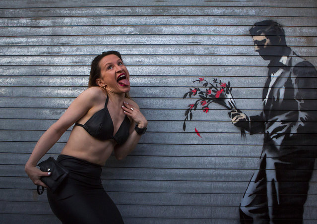 A dancer poses with a new installation of art by British graffiti artist Banksy painted on the front door of the Hustler Club in New York October 24, 2013. (Photo by Eric Thayer/Reuters)