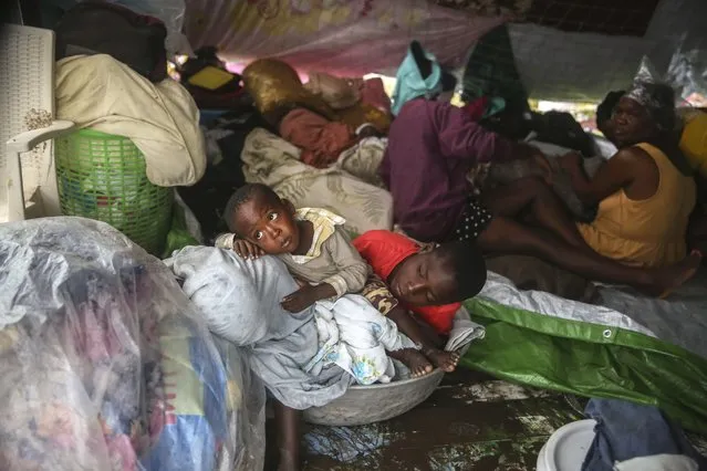 Earthquake-displaced people sit under blankets to shield themselves from the rain, the morning after Tropical Storm Grace swept over Les Cayes, Haiti, early Tuesday, August 17, 2021, three days after a 7.2-magnitude earthquake. (Photo by Joseph Odelyn/AP Photo)