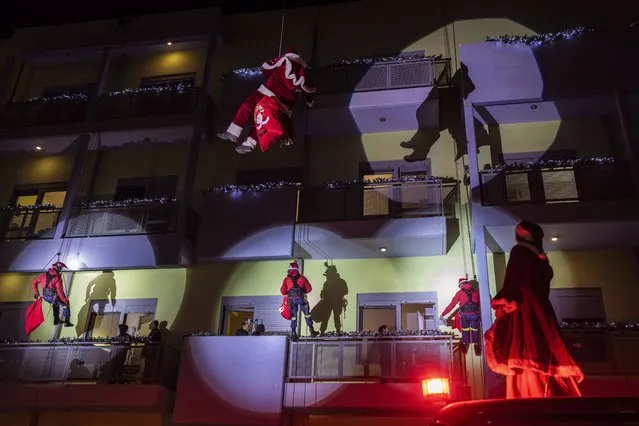 Firefighters dressed as Santas and dangled on ropes as they scale down the Athens' main children's hospital to deliver Christmas presents to young cancer patients spending the holidays in hospital, in Athens, Thursday, December 22, 2022. (Photo by Petros Giannakouris/AP Photo)