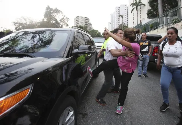 A supporter of Venezuela's President Nicolas Maduro kicks a car that is part of the caravan that moves Venezuela's self-proclaimed interim president Juan Guaido, during his arriving at a rally in Caracas, Venezuela, Friday, March 29, 2019. The International Federation of Red Cross and Red Crescent Societies said Friday that it is poised to deliver aid to Venezuela, warning that it will not accept any interference from President Nicolas Maduro or opposition leader Juan Guaido. (Photo by Boris Vergara/AP Photo)