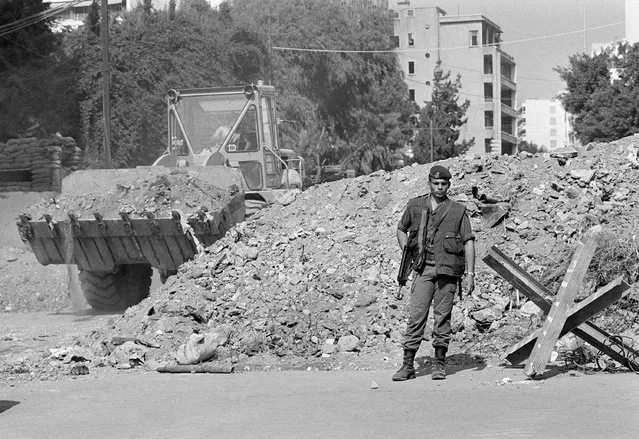 While a French trooper stands guard, an earth mover constructs a block of a street to beef up security near French paratroop command two days after it was attacked by a terrorist bomb, in Beirut, Tuesday, October 25, 1983. Judicial authorities in France have sent a judicial request to Lebanon's prosecution, Wednesday, March 8, 2023, asking them to detain two people suspected in being involved in a 1983 bombing in Beirut that killed dozens of French troops, judicial officials said Wednesday. (Photo by Azakir/AP Photo)
