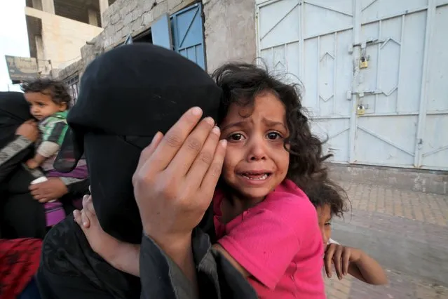 A girl cries next to her mother covering her face as they flee from an airstrike on an army weapons depot in Yemen's capital Sanaa May 11, 2015. (Photo by Mohamed al-Sayaghi/Reuters)