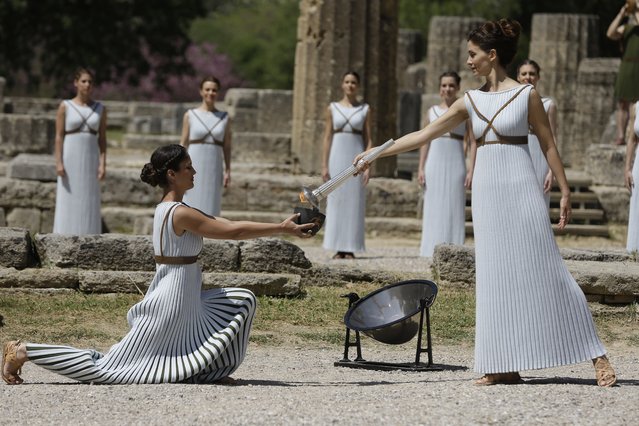 Actress Katerina Lehou, right, as high priestess, lights a pot with the Olympic Flame, during the final dress rehearsal of the lighting of the Olympic flame at Ancient Olympia, in western Greece on Wednesday, April 20, 2016. (Photo by Petros Giannakouris/AP Photo)
