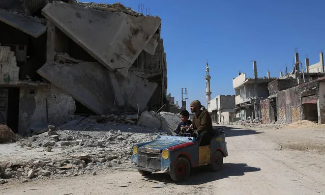 A Syrian man drives a home- made toy car in the rebel- held town of Beit Naim, in the eastern Ghouta region on the outskirts of the capital Damascus, on March 7, 2017. (Photo by Amer Almohibany/AFP Photo)