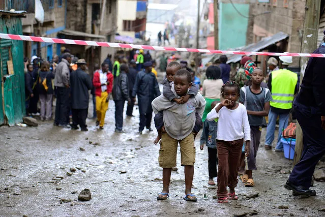 Children walk near rescue operations of residents feared trapped in the rubble of a six-storey building that collapsed after days of heavy rain, in Nairobi, Kenya April 30, 2016. (Photo by Harman Kariuki/Reuters)