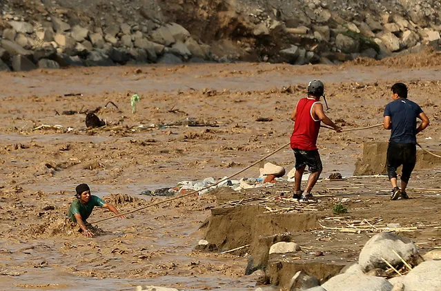 People try to cross the Rimac River after rivers breached their banks due to torrential rains, causing flooding and widespread destruction in Huachipa, Lima, Peru, March 19, 2017. (Photo by Mariana Bazo/Reuters)