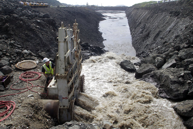 Canal worker opens the water valves to flood the first access channel that will join the new locks in the Pacific area of the Panama Canal in Panama City October 20, 2011. (Photo by Alberto Lowe/Reuters)