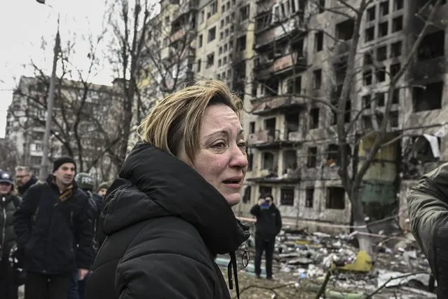 A woman reacts as she stands outside destroyed apartment blocks following shelling in the northwestern Obolon district of Kyiv on March 14, 2022. Two people were killed on March 14, 2022, as various neighbourhoods of the Ukraine capital Kyiv came under shelling and missile attacks, city officials said, after the Russia's military invaded the Ukraine on February 24, 2022. (Photo by Aris Messinis/AFP Photo)