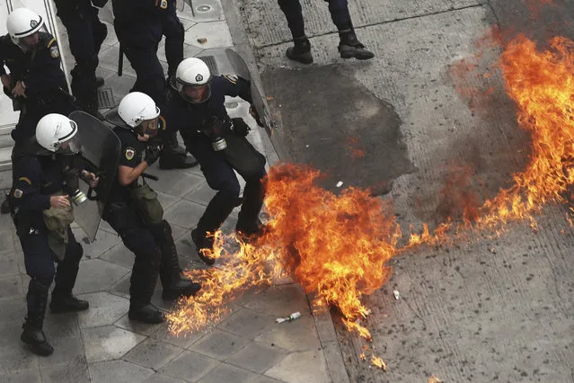 Riot police officers try to avoid a patrol bomb thrown by protester during a nationwide general strike demonstration. in Athens Wednesday, May 17, 2017. Greek workers walked off the job across the country Wednesday for an anti-austerity general strike that was disrupting public and private sector services across the country. (Photo by Petros Giannakouris/AP Photo)