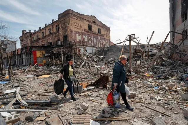 Residents carry their belongings near buildings destroyed in the course of Ukraine-Russia conflict, in the southern port city of Mariupol, Ukraine on April 10, 2022. (Photo by Alexander Ermochenko/Reuters)