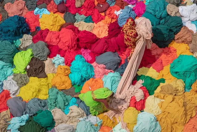 Workers sort through colourful piles of fabrics ready to be made into garments in Narayanganj, Bangladesh on March 29, 2022. The workers are sorting and selecting the fabrics according to colour, quality and the demand of the buyers. The fabrics are generally used in apparel manufacturing process. They are piled up for sorting and grading as well as to dry in the sun with moisture being removed from the dying process. (Photo by Joy Saha/ZUMA Press Wire/Rex Features/Shutterstock)