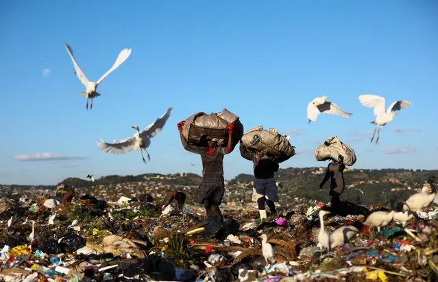 Women carry garbage bags after collecting recyclable materials among garbage at the Goudkoppies landfill site near Eldorado Park in the south of Johannesburg, South Africa, April 13, 2022. (Photo by Siphiwe Sibeko/Reuters)