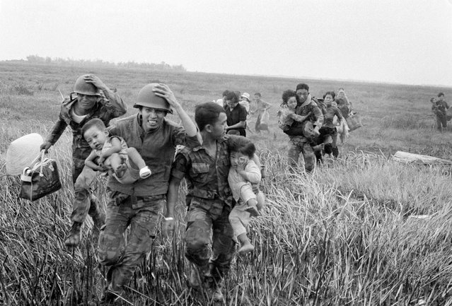 South Vietnamese Rangers rush children to a helicopter for evacuation from the Duc Hue base camp, about 35 miles northwest of Saigon, on April 5, 1974. The camp had been under enemy artillery attack for more than a week. (Photo by Associated Press)