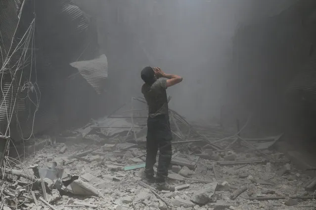 A Syrian man reacts following a reported air strike by Syrian government forces in the rebel-held neighbourhood of Bustan al-Qasr on June 5, 2016. (Photo by Baraa Al-Halabi/AFP Photo)