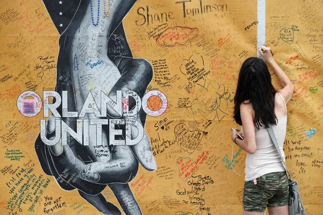 Mary Beth Nickerson signs the wall outside of Pulse Nightclub while visiting the memorial on the one year anniversary of the shooting in Orlando, Florida June 12, 2017. (Photo by Scott Audette/Reuters)