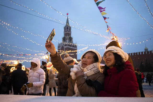 Tourists take a selfie in Red Square decorated for New Year celebrations, with the the Kremlin's Spasskaya Tower in the background, in Moscow, Russia, Monday, December 30, 2019. (Photo by Pavel Golovkin/AP Photo)
