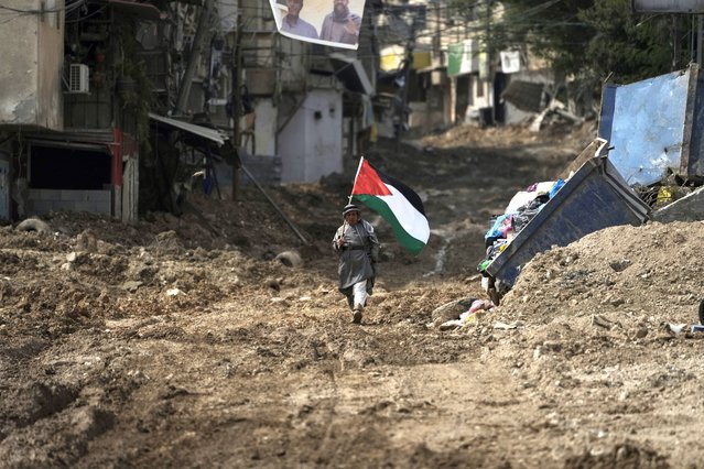 Palestinian activist Khairi Hanoon walks with the Palestinian flag on a damaged road following an Israeli army raid in Tulkarem, West Bank, on Tuesday, September 3, 2024. (Photo by Majdi Mohammed/AP Photo)