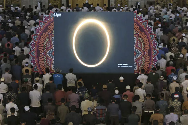 Muslim men perform a special “kusoof” prayer as a live report of the annular solar eclipse is broadcasted on a large screen at a mosque in Surabaya, East Java, Indonesia, Thursday, December 26, 2019. People along a swath of southern Asia gazed at the sky in marvel on Thursday at a “ring of fire” solar eclipse. (Photo by AP Photo)