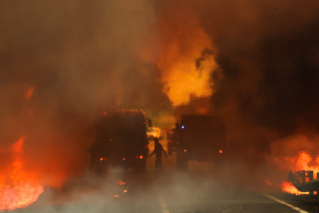 Firefighters try to extinguish a wildfire on a road in Junqueiro, Agueda, Portugal on September 17, 2024. (Photo by Pedro Nunes/Reuters)