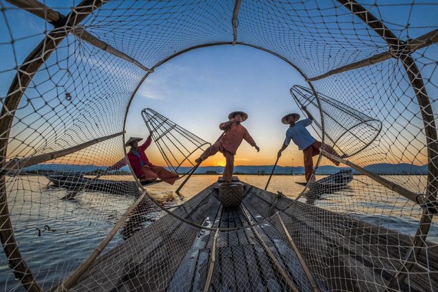 Fishermen use traditional cone-shaped nets on Inle lake in Myanmar in February 2022. The men steer their boats with an oar that they control with their feet. They throw the net into the water and push it down so it sinks to the bottom, then drag it back to the surface with the fish trapped inside. (Photo by Alahattin Kanlioglu/Solent News)