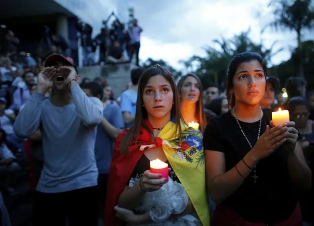 Anti-government demonstrators hold candles during a vigil in honor of those who have been killed during clashes between security forces and demonstrators in Caracas, Venezuela, Monday, July 31, 2017. Many analysts believe Sunday's vote for a newly elected assembly that will rewrite Venezuela’s constitution will catalyze yet more disturbances in a country that has seen four months of street protests in which at least 125 people have died. (Photo by Ariana Cubillos/AP Photo)