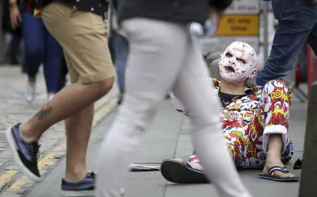 A performer reacts while attracting passers by, as acts gather amongst the crowds at the Edinburgh Fringe Festival on the Royal Mile in Edinburgh, Scotland, Sunday August 6, 2017. The annual Edinburgh Festival attracts thousands of tourists to the city with hundreds of events, with some traditional theatrical performances and some avant-garde street acts. (Photo by David Cheskin/PA via AP Photo)