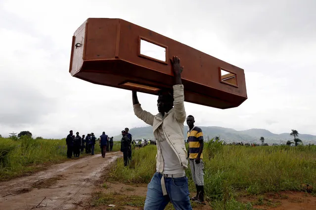A man carries an empty coffin at the Paloko cemetery in Waterloo, Sierra Leone on August 17, 2017. (Photo by Afolabi Sotunde/Reuters)