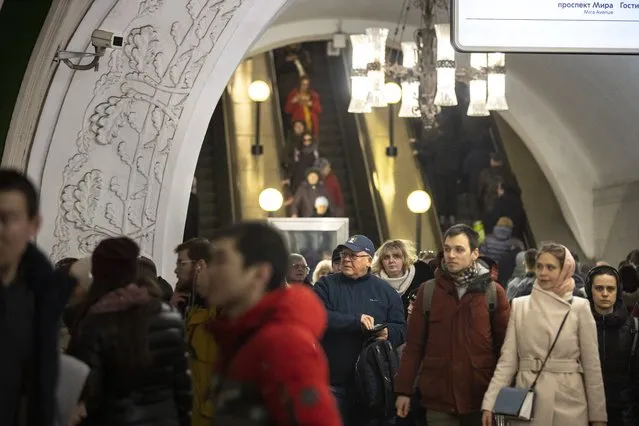 In this photo taken on Saturday, February 22, 2020, a surveillance camera, top left, is seen as people walk down in a Moscow's Metro (subway) station in Moscow, Russia. Metro workers were instructed to stop passengers from China and ask them to fill out a questionnaire about the purpose of their visit to Russia, address of residence, health condition and whether they underwent quarantine upon arrival. (Photo by Alexander Zemlianichenko/AP Photo)