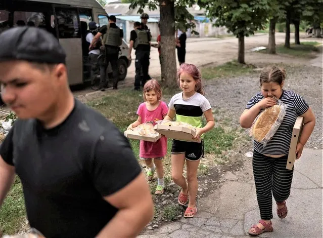 Police officers distribute aid to local residents, amid Russia's attack on Ukraine, in the town of Krasnohorivka, in Donetsk region, Ukraine on June 16, 2022. (Photo by Gleb Garanich/Reuters)