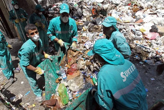 Lebanese street cleaners start to collect rubbish from the streets of Beirut a week after protesters shut down the country's largest landfill leaving piles of uncollected trash all over the Lebanese capital on July 26, 2015. Local villagers fed up of living next to the Naameh landfill, the endpoint for waste produced by around half of Lebanon's four million citizens, blocked the entry of the facility preventing any new trash from being dumped, in demand for its closure. (Photo by Anwar Amro/AFP Photo)