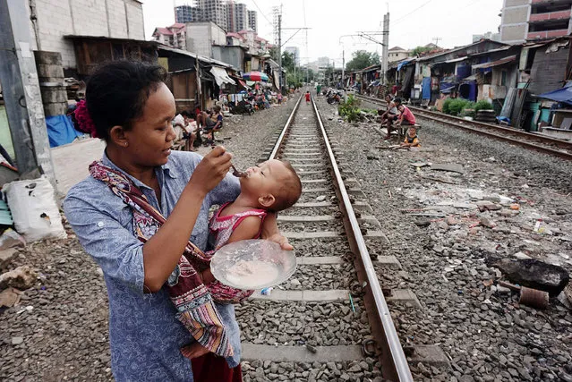 A woman feeds her baby near the railway tracks at the slum in Jakarta, Indonesia on July 11, 2016. Indonesia is the most populous country in Southeast Asia. The region has experienced significant economic growth in recent years, yet is home to significant rates of economic inequality. (Photo by Jefta Images/Barcroft Images)