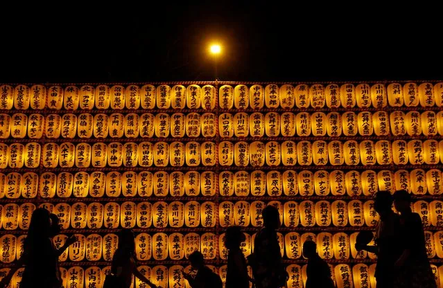 Visitors are silhouetted in front of lanterns during the annual Mitama Festival at the Yasukuni Shrine, where more than 2.4 million war dead are enshrined, in Tokyo, Japan, July 13, 2022. (Photo by Kim Kyung-Hoon/Reuters)