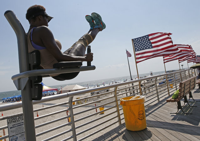 Karma Scott, 19, does leg lifts at a fitness station on the boardwalk, Wednesday, July 19, 2017, in Long Beach, N.Y. Temperatures in the 90's drew hundreds of people seeking relief from the warmth to the ocean where stiff breezes cooled them off. Scott said she exercises regularly after trimming down from 250 pounds in about a year and a half. (Photo by Kathy Willens/AP Photo)