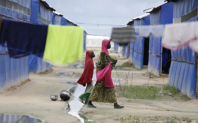 I n this Saturday August 27, 2016, file photo, a woman and her child walk past the laundry at a camp for people displaced by Islamist Extremist in Maiduguri, Nigeria. (Photo by Sunday Alamba/AP Photo/File)