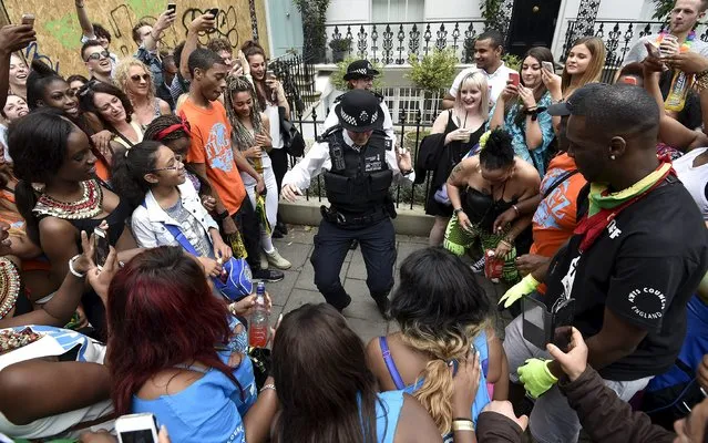 Revellers watch as police officers dance in the street at the Notting Hill Carnival in west London, August 30, 2015. (Photo by Toby Melville/Reuters)
