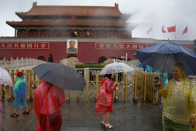 Tourists hold umbrellas as they stand in front of the Tiananmen Gate and a giant portrait of Chinese late Chairman Mao Zedong on a day of heavy rain in Beijing, China, July 20, 2016. (Photo by Thomas Peter/Reuters)