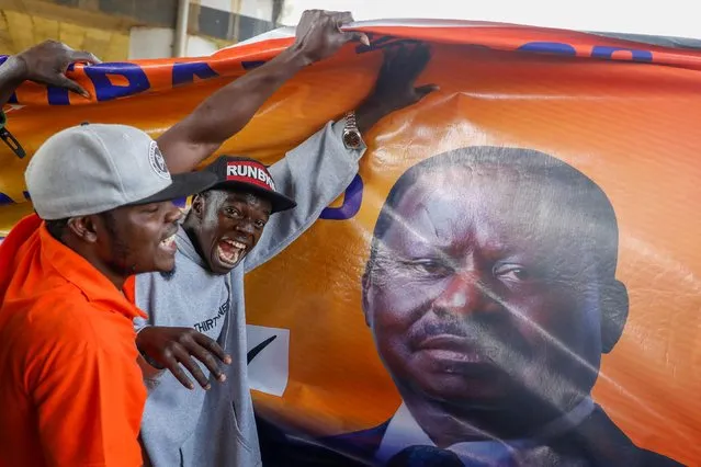 People carry a banner of Kenya's opposition leader and presidential candidate Raila Odinga of the Azimio La Umoja (Declaration of Unity) One Kenya Alliance as they wait for the announcement of the election results, in Kisumu, Kenya on August 15, 2022. (Photo by Baz Ratner/Reuters)